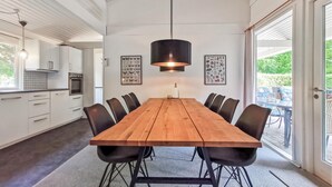 Un comedor moderno con una mesa de madera, sillas negras y una lámpara colgante.