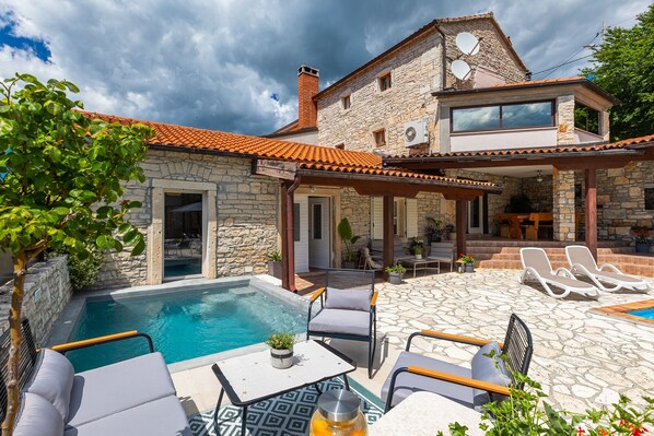 A stone house with a swimming pool, outdoor seating, and a patio area.