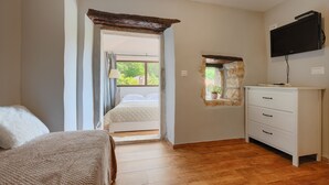 A bedroom with a bed, a dresser, a television, and a window with a view of greenery. - Villa Antoli (Istria - Jakovici) (Jakovici)