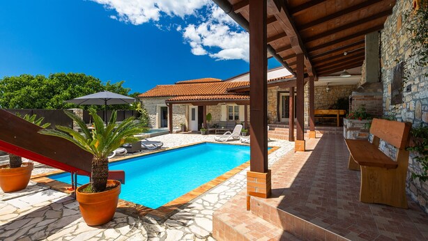A poolside area with a stone patio, lounge chairs, and a covered seating area. - Villa Antoli (Istria - Jakovici) (Jakovici)
