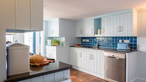 A modern kitchen with white cabinets, a black countertop, and a blue-tiled backsplash.