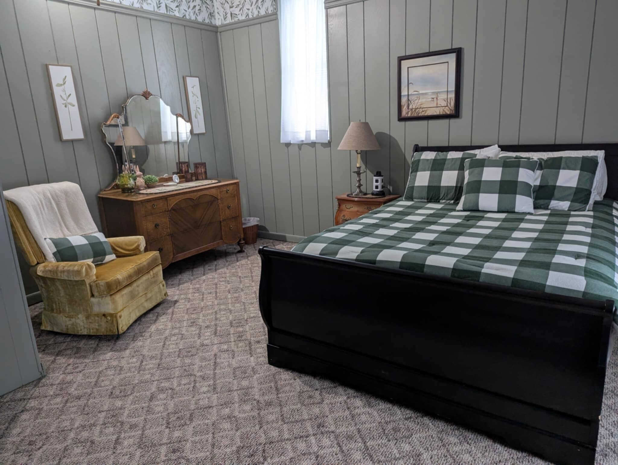 A bedroom with a bed, a dresser, a chair, and a nightstand.