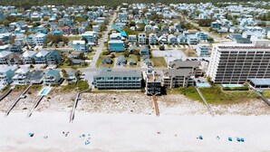 Vista aérea de una zona residencial costera con casas, una playa y un edificio grande de varios pisos.