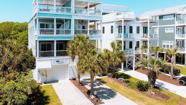 Un edificio residencial de varios pisos con balcones, un garaje y un césped bien cuidado con palmeras.