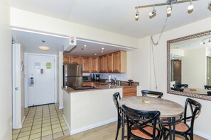 A kitchen with wooden cabinets, stainless steel appliances, a dining area with a table and chairs, and a large mirror.
