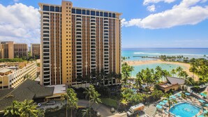 A high-rise hotel with a pool area, beach view, and multiple balconies.
