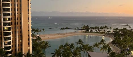 A high-rise hotel with a pool area, beach, and ocean view.