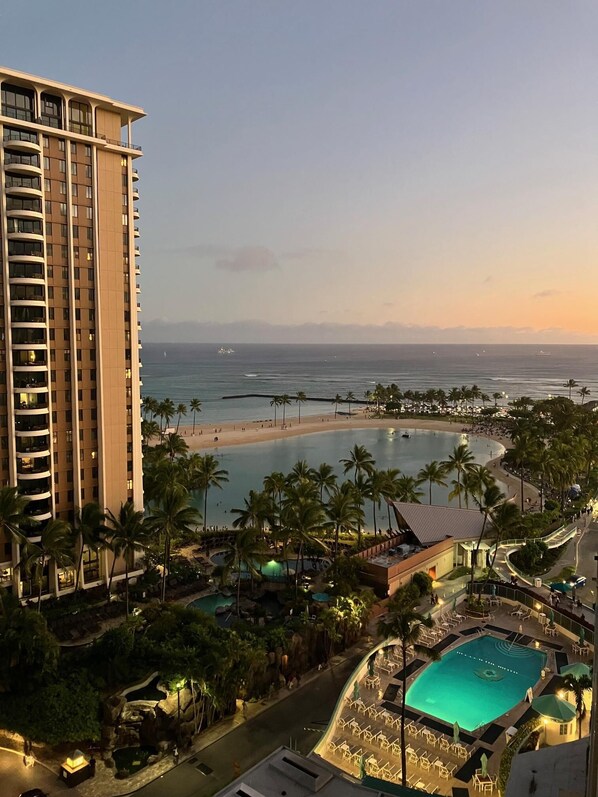 A high-rise hotel with a pool area, beach, and ocean view.