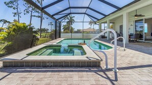 A covered outdoor swimming pool with a hot tub, surrounded by a patio area with outdoor furniture. - Golf Course View, Putting Green, Heated Pool and Spa - Villa Fairway to Heaven - Roelens (Cape Coral)