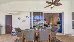 A dining area with a table and four chairs, a ceiling fan, and a view into the kitchen. - Golf Course View, Putting Green, Heated Pool and Spa - Villa Fairway to Heaven - Roelens (Cape Coral)