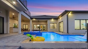 Una casa moderna con piscina, patio coperto e balcone.