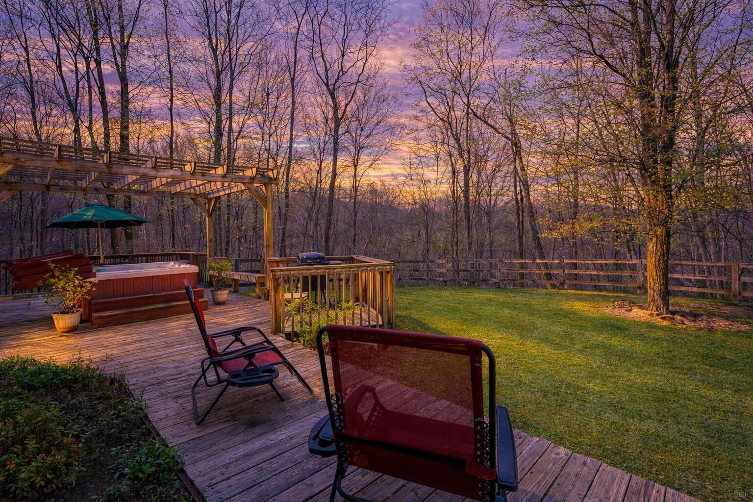 Een houten terras met buitenmeubilair, een barbecue en een pergola.