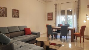 A living room with a grey sectional sofa, a small round coffee table, and a dining area with a wooden table and chairs. - 3 bedroom amazing apartment in Palermo (Palermo)