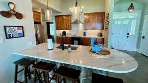 Una cocina con una isla grande, taburetes de madera y luces colgantes.