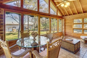 A wooden cabin with a glass table and wicker chairs, large windows, and a view of a lake. - Lakefront Leesburg Home w/ Private Dock & Ramp! (Leesburg)