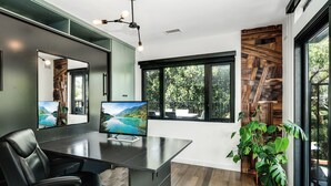 Un espace de bureau moderne doté d’un grand bureau, de deux écrans, d’un fauteuil en cuir et offrant une vue sur un paysage montagneux grâce à de grandes fenêtres.