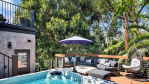 Un espace piscine doté d’un jacuzzi, de coins salon extérieurs et d’une pergola avec un fauteuil suspendu.