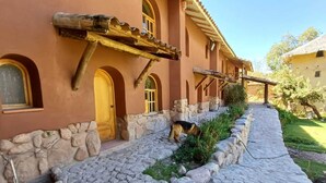Un chemin de pierres mène à un bâtiment doté de fenêtres en arc de cercle et d’une porte en bois.