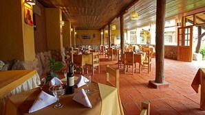 Un restaurant avec des tables et des chaises en bois, un mur en pierre et un sol carrelé.