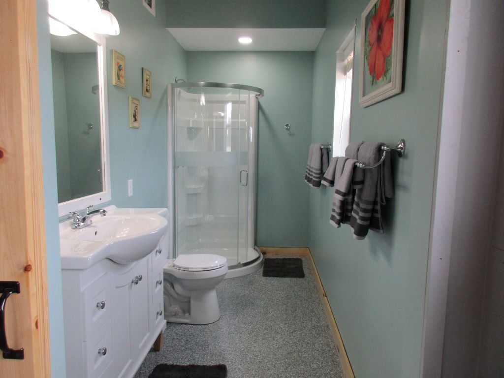 A bathroom with a shower, toilet, sink, and towel rack.