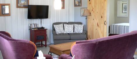 A living room with a sofa, a coffee table, a television, and a fireplace.
