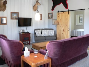 Een woonkamer met een bank, een salontafel, een televisie en een open haard.