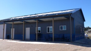 A single-story industrial building with a covered outdoor area, a door, and windows. - Country setting near Custer, Wi-Fi, AC, pet friendly w/fee. No cleaning fee. (Custer)
