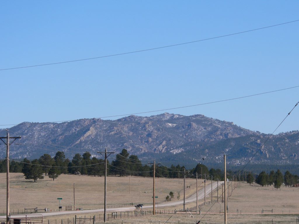 Un paysage rural avec un chemin de terre qui mène à une chaîne de montagnes.