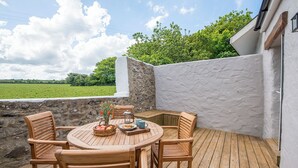 An outdoor patio with a round wooden table, four wooden chairs, and a stone wall. - Bwthyn Clyd, Holiday Cottage Llanrhian, Sleeps 4, 2 bedrooms,  bathrooms (Haverfordwest)