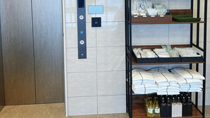 A modern elevator with a control panel, a wall-mounted shelf with toiletries, and a clock. - Nplus HOTEL Tokyo Nihonbashi (Tokyo)