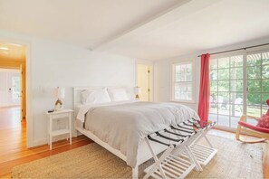 A bedroom with a bed, nightstands, a window with a view, and a red curtain.