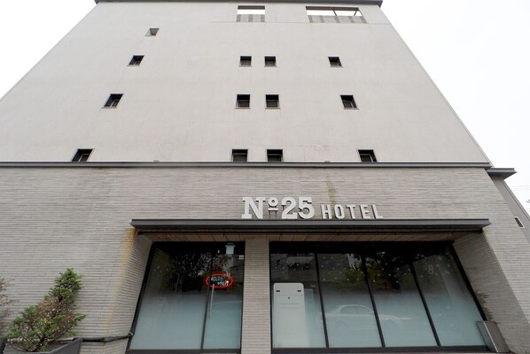 Un edificio alto y moderno con el letrero "N°25 HOTEL" sobre la entrada.