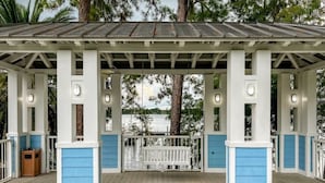 A covered outdoor area with a wooden deck, white and blue railings, and a view of the water. - Orlando | Family Splash Stay | Pool + Waterpark | 2BR Condo (Orlando)