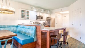 Una cocina moderna con armarios blancos, microondas integrado y refrigerador de acero inoxidable.