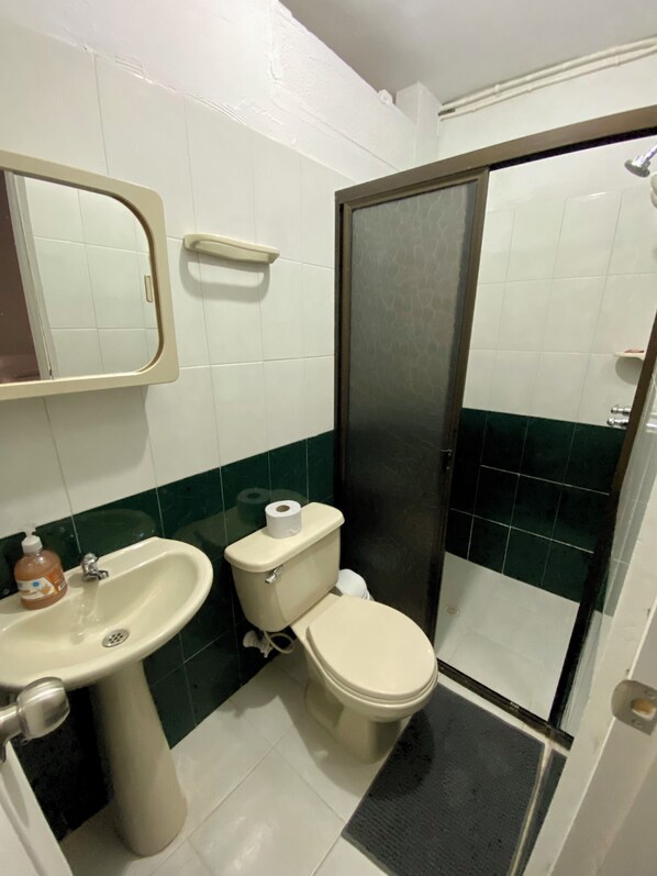A bathroom with a toilet, sink, and mirror.