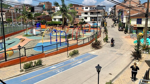 A playground with various play structures, a bike lane, and residential buildings in the background. - Encantadora Casa en el Corazón de Guatapé, Perfecta Para Familias y Grupos! (Guatape)