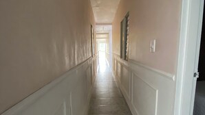 A long, narrow hallway with white wainscoting and a tiled floor. - Encantadora Casa en el Corazón de Guatapé, Perfecta Para Familias y Grupos! (Guatape)