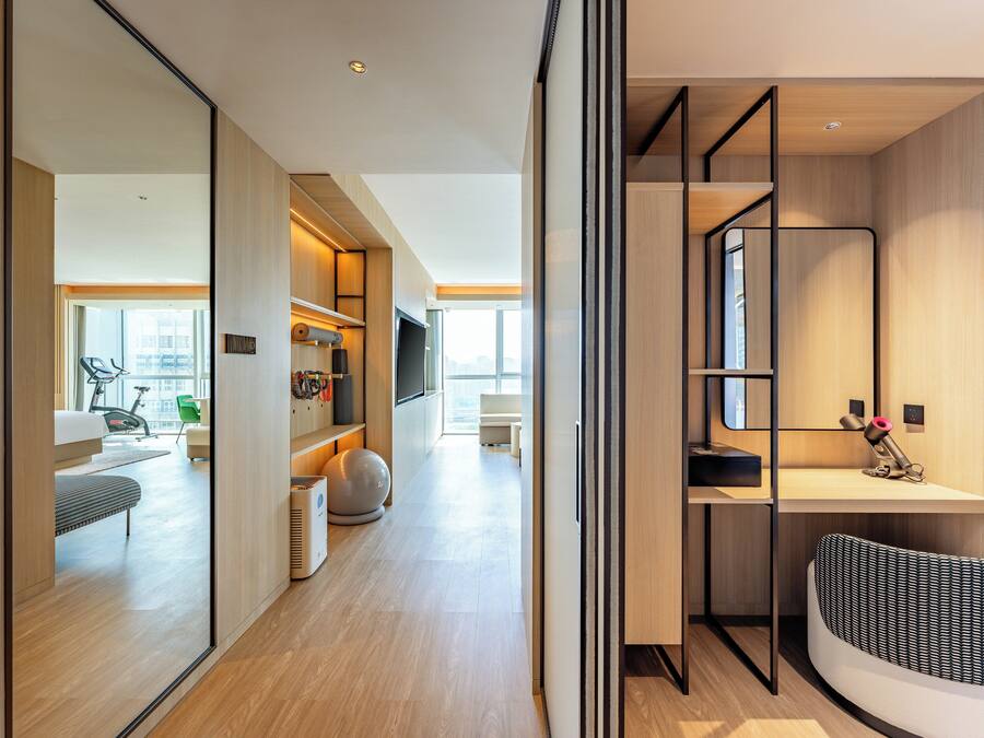A modern interior with a wooden floor, a desk with a computer, a chair, and a large mirror.