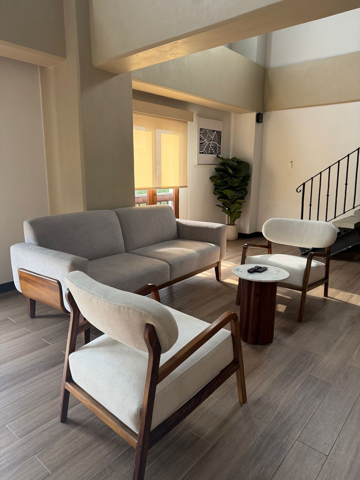 A living room with a sectional sofa, two armchairs, a coffee table, and a staircase.