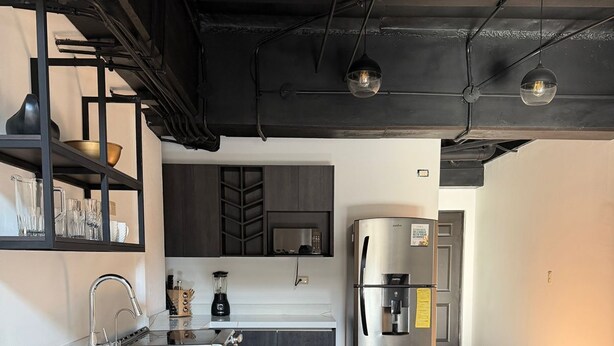Una cocina moderna con una isla grande, electrodomésticos de acero inoxidable y taburetes de bar de madera.