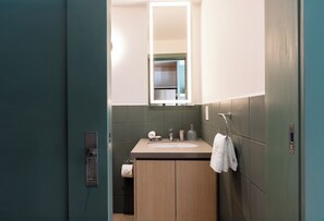 A modern bathroom with a wooden vanity, a mirror, a sink, and a towel hanging on the wall. - Cayalá Lofts (Guatemala City)