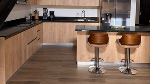 Una cocina moderna con armarios de madera, encimera negra, electrodomésticos de acero inoxidable y una escalera.