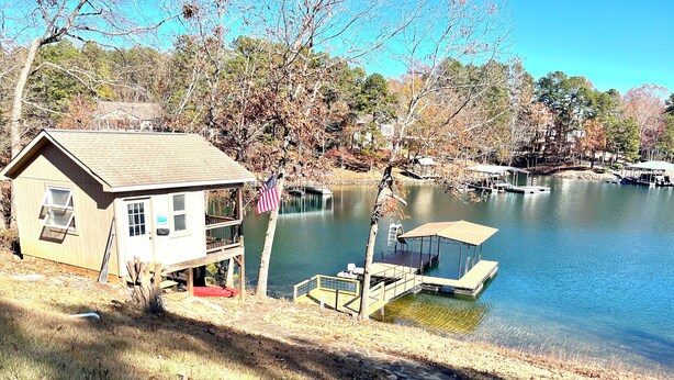 Un chalet au bord du lac, doté d’un quai, d’un sentier en pierre et d’une petite terrasse.