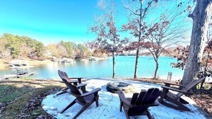 Une terrasse au bord du lac, avec des fauteuils Adirondack et un foyer.