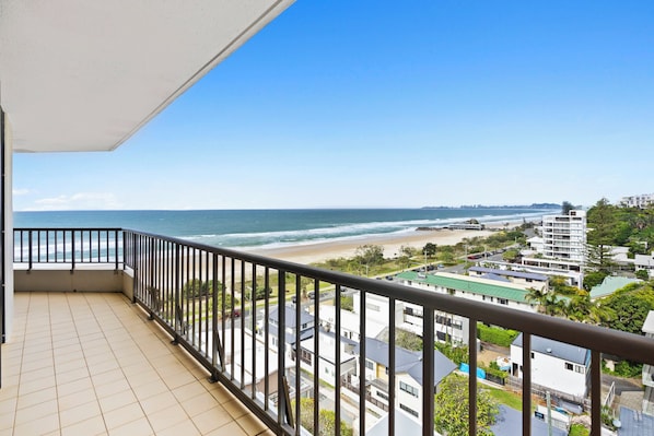Un balcon avec vue sur une plage et des immeubles d’habitation.