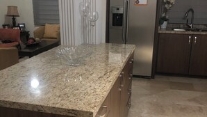 A kitchen with a granite countertop, stainless steel refrigerator, and wooden cabinets.