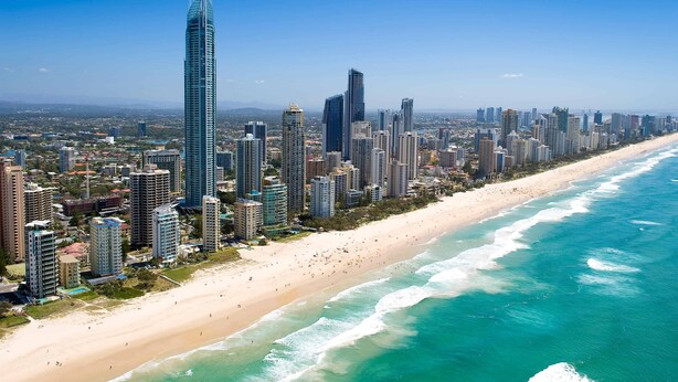 Un paisaje costero urbano con edificios altos, una playa arenosa y un cielo azul despejado.