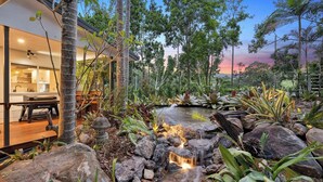 Una casa moderna con cocina, comedor y jardín con una pequeña cascada.