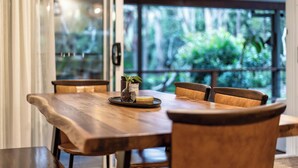 Una mesa de madera con sillas, una planta pequeña en maceta y una bandeja con monedas.