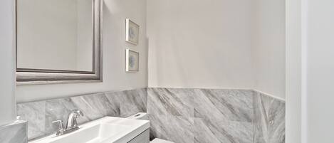 Une salle de bain avec un lavabo blanc, un miroir et des toilettes.